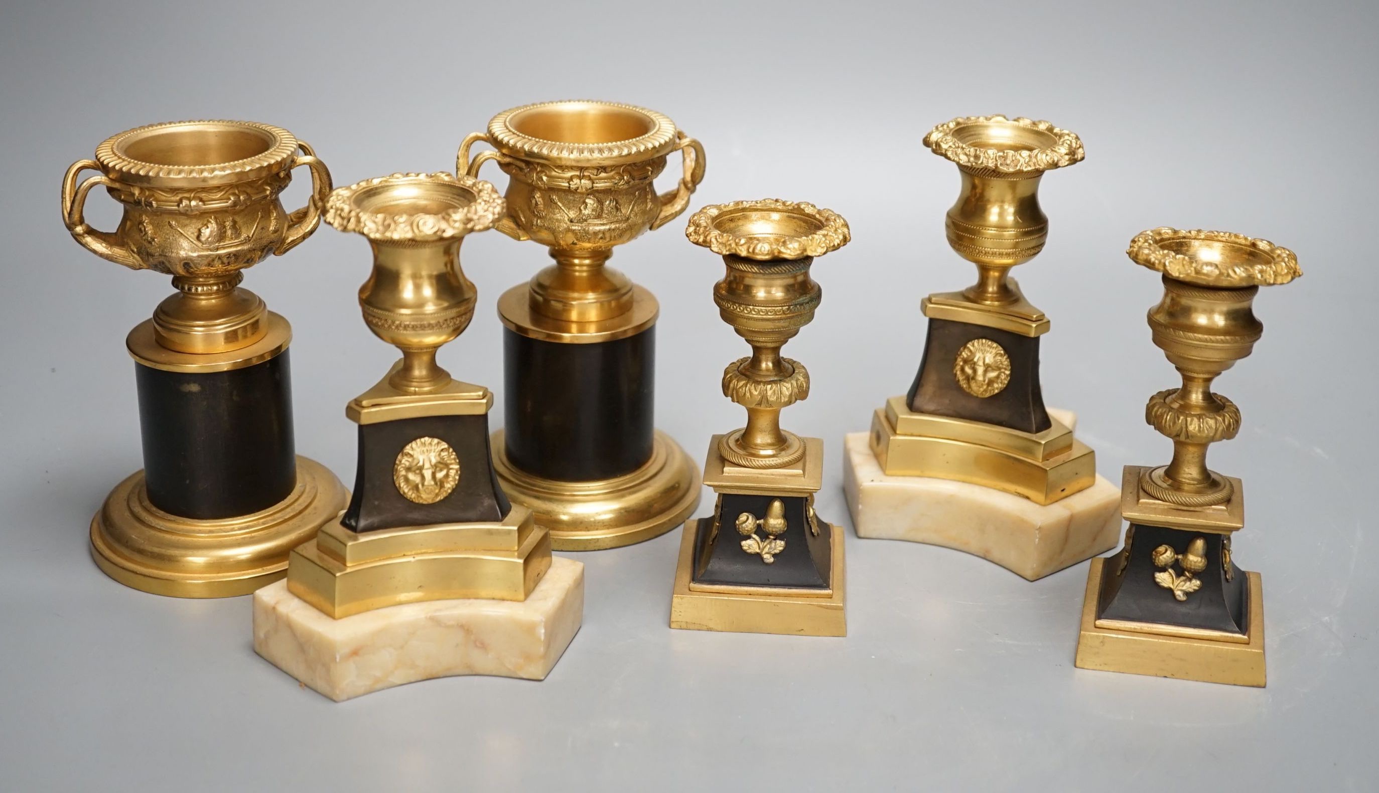 A pair of Louis XVI style ormolu and bronze models of campana urns and two similar pairs of Empire style candlesticks